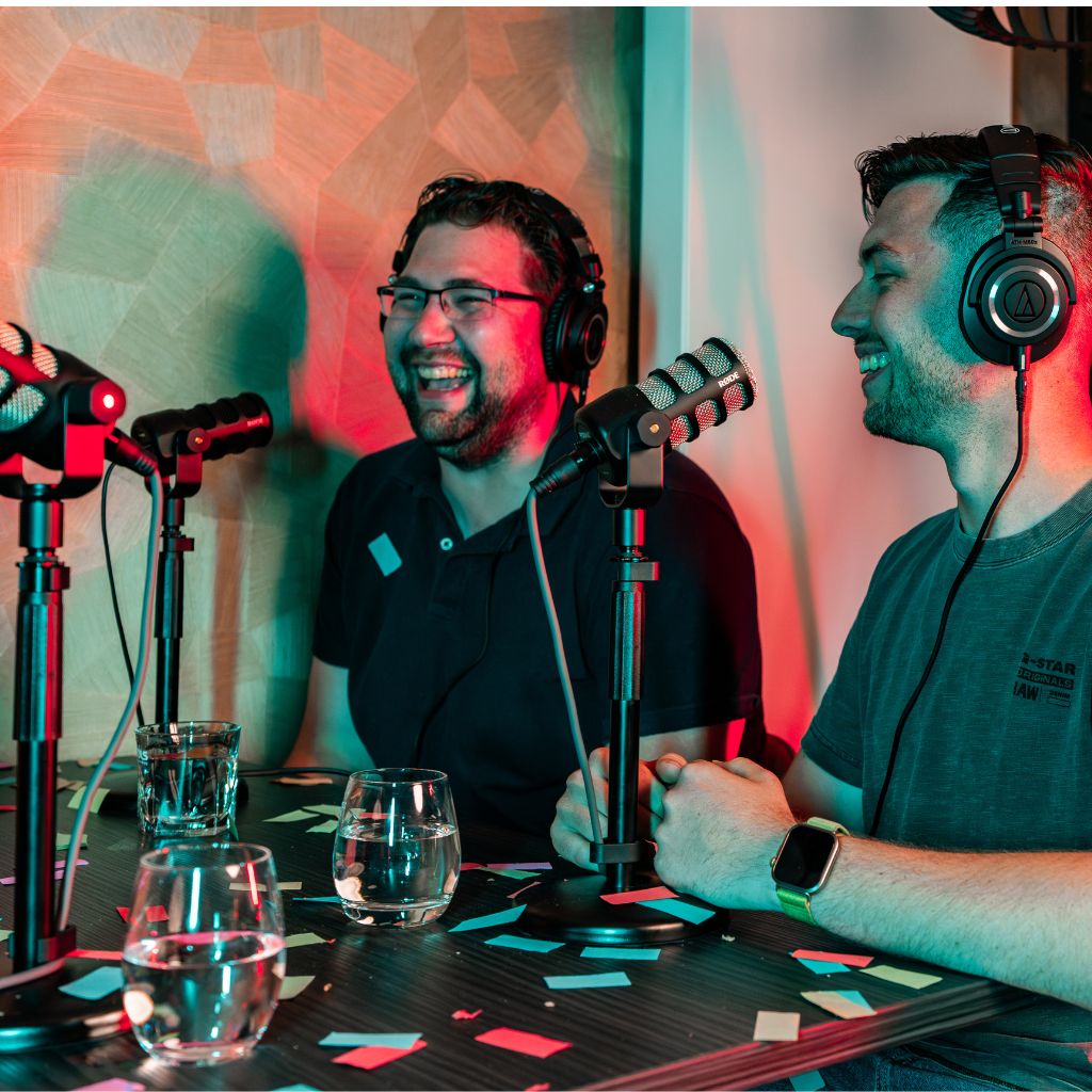 Podcastopname tijdens een evenement met publiek op de achtergrond.