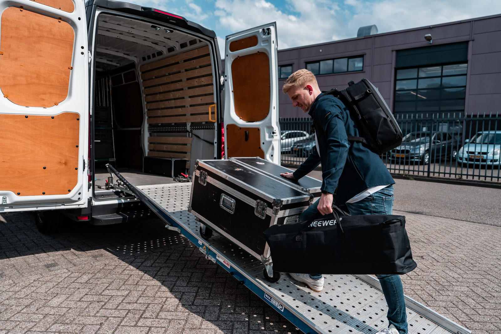 Jesse laadt een flightcase met opnameapparatuur in de bus.